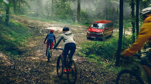 Volkswagen Multivan im Wald mit Bikern im Vordergrund