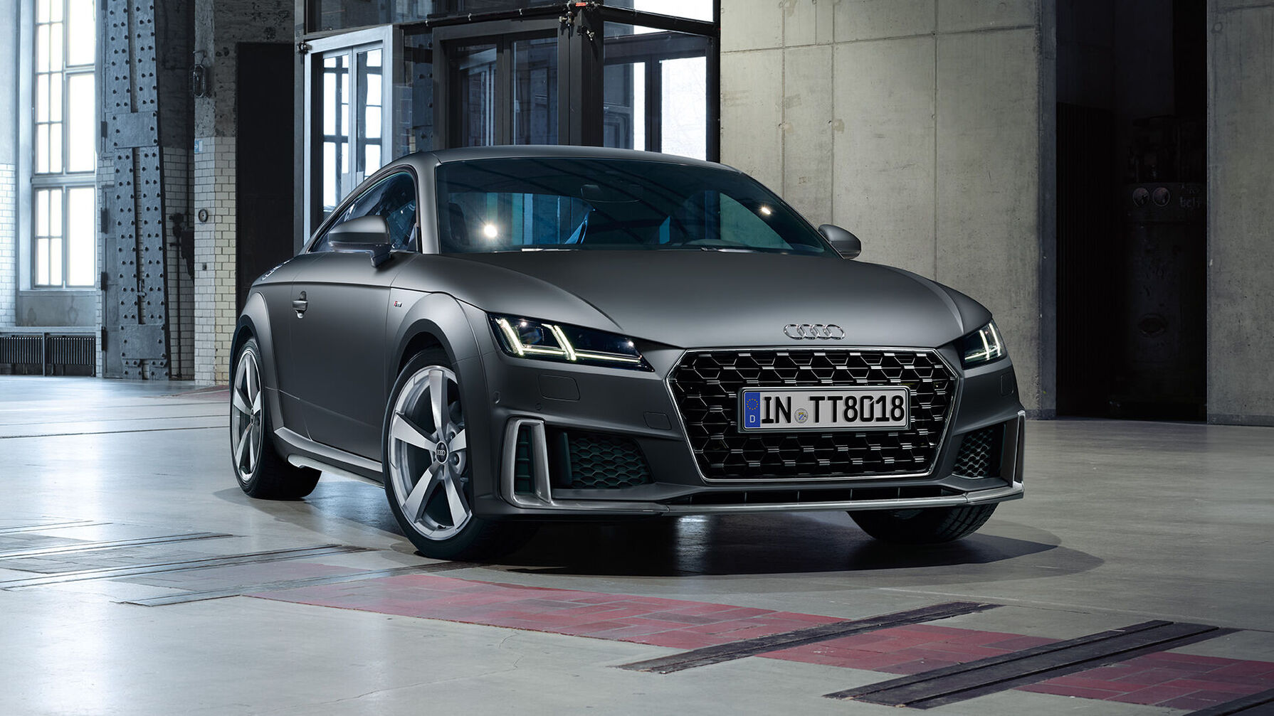 Der Audi TT in grauer Lackierung überzeugt mit kompakter Sportwagenform, tief sitzender Front, markantem Wabengrill und präzise gestalteten LED-Scheinwerfern.
