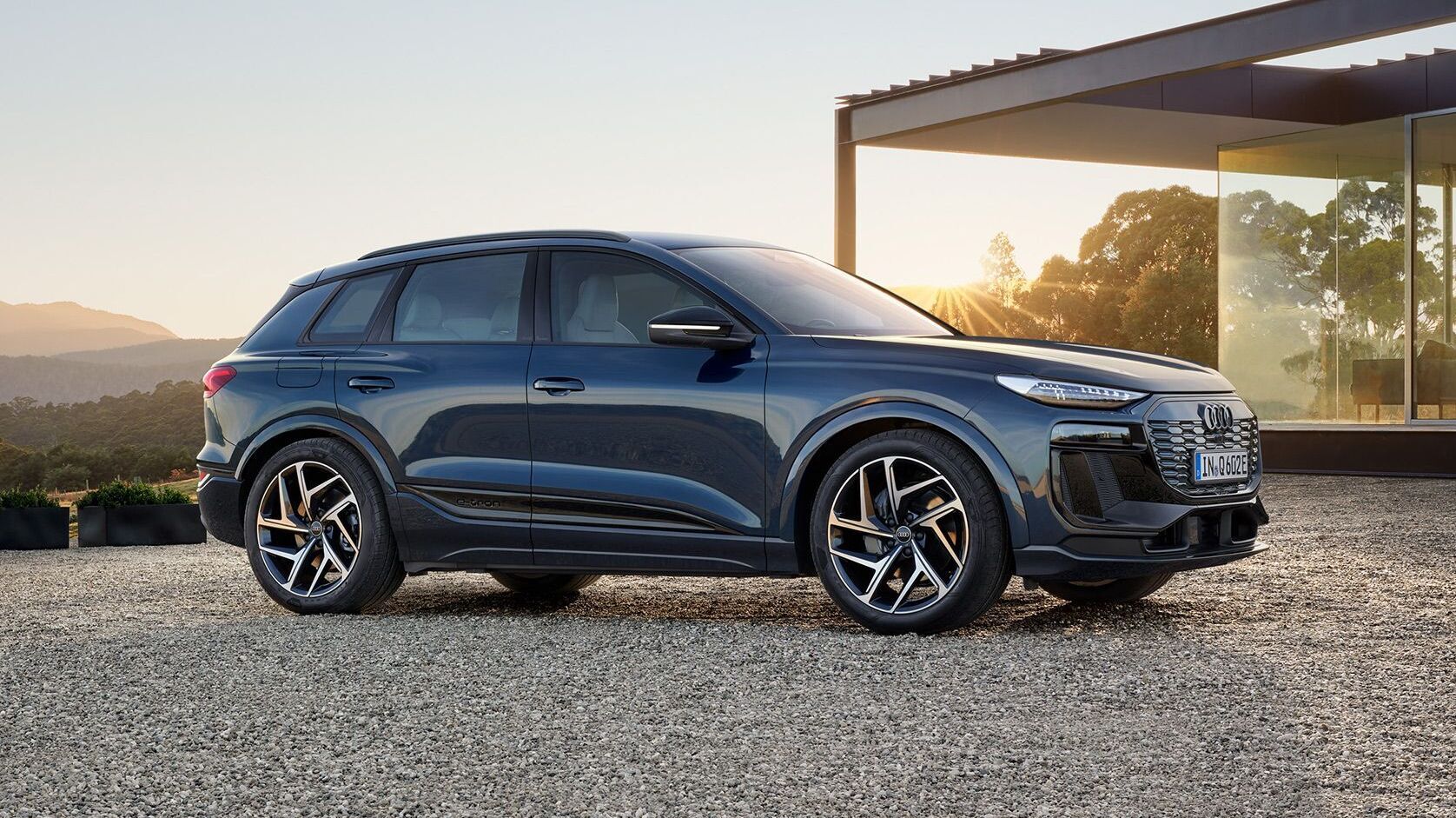 Audi Q6 SUV e-tron vor einem modernen Haus mit großer Fensterfront
