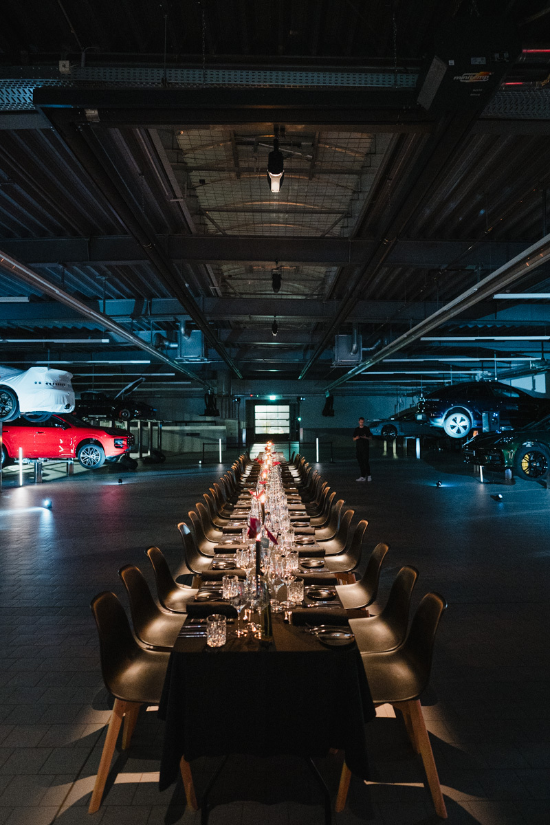 Eine lange Tafel ist in einer Sportwagenhalle aufgebaut.