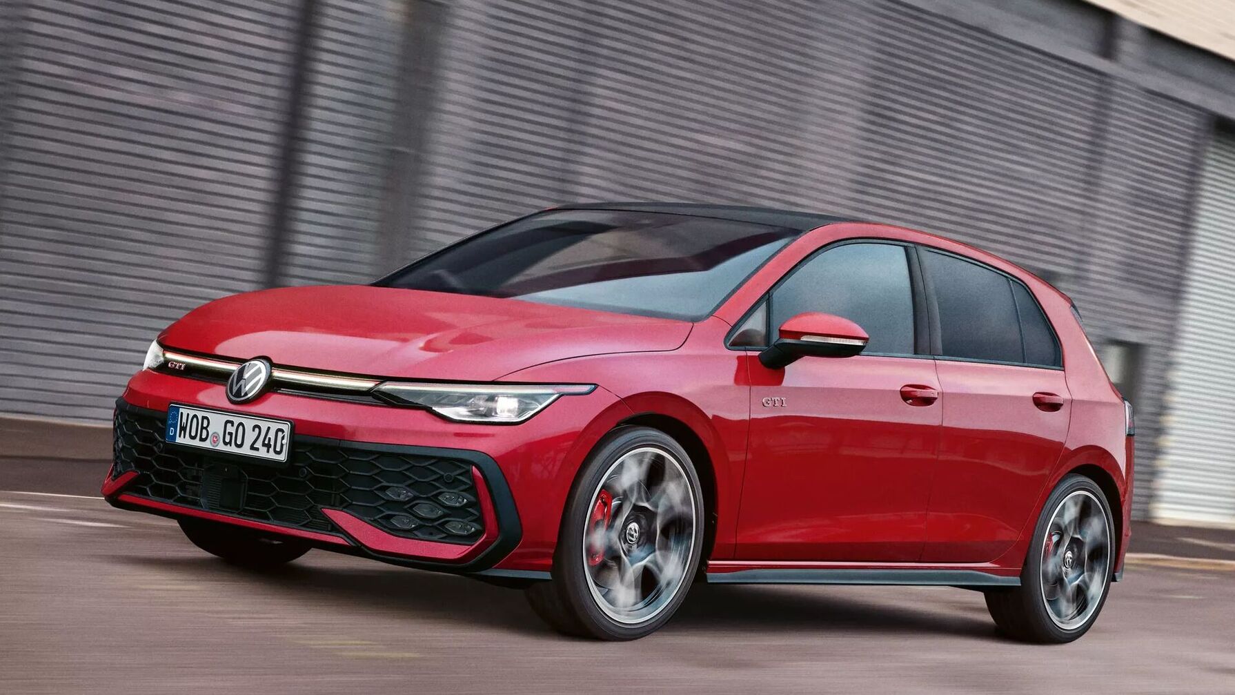 Der rote VW Golf GTI fährt dynamisch durch die Stadt und zeigt seine markante Front mit sportlichen Details.