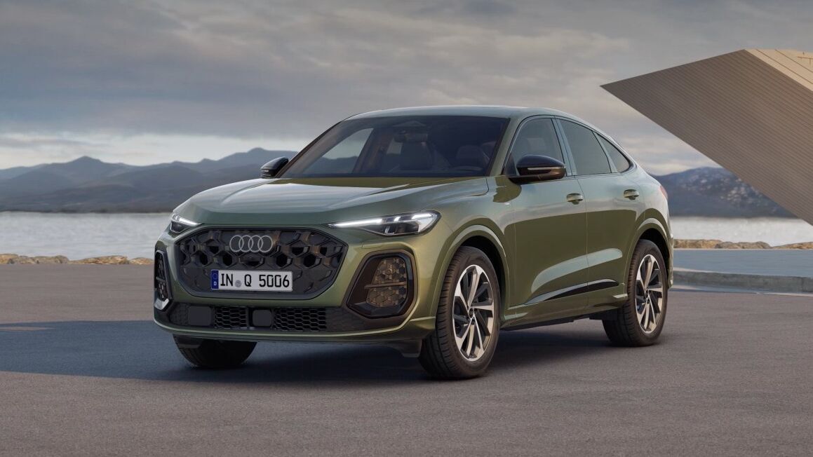 Audi Q5 Sportback in Distriktgrün Metallic steht vor moderner Architektur, mit markantem Singleframe-Grill in Wabenoptik, LED-Matrix-Scheinwerfern und 20-Zoll-Leichtmetallrädern.