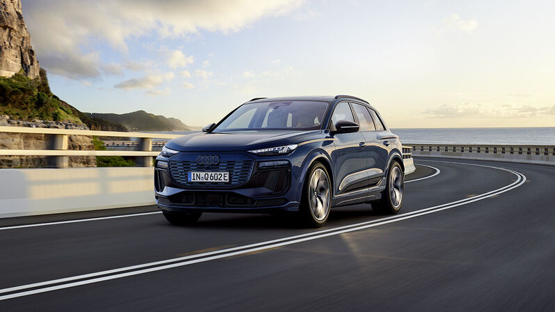 Audi Q6 e-tron in Blau, fährt dynamisch die Straße entlang.
