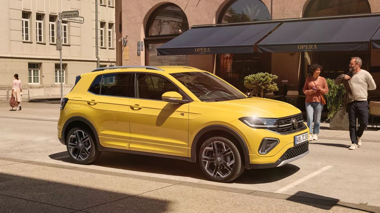 Der gelbe VW T-Cross steht vor einem Café in der Innenstadt. Kompakt gebaut und flexibel im Innenraum.