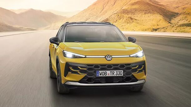 Der gelbe VW T-Roc fährt dynamisch durch eine weite Landschaft. Das markante Frontdesign und die erhöhte Sitzposition prägen seinen SUV-Charakter.