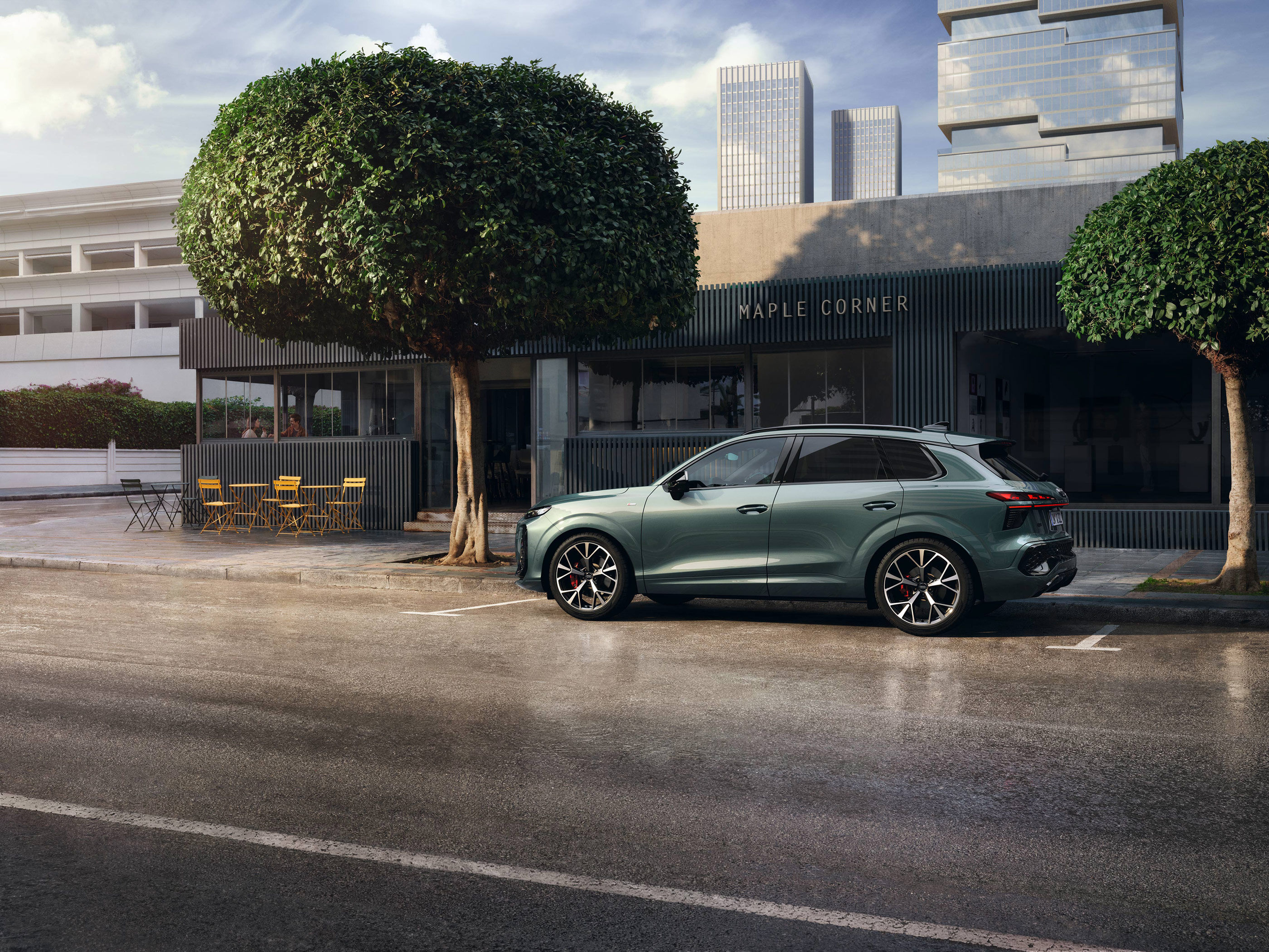 Audi Q3 parkt unter einem Baum in der Stadt (2025) in der Seitenansicht 