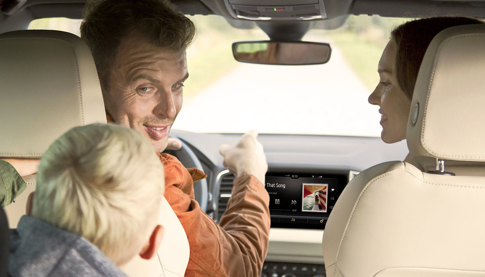 Eltern schauen sich lächelnd im Auto nach ihrem Sohn im Rücksitz um