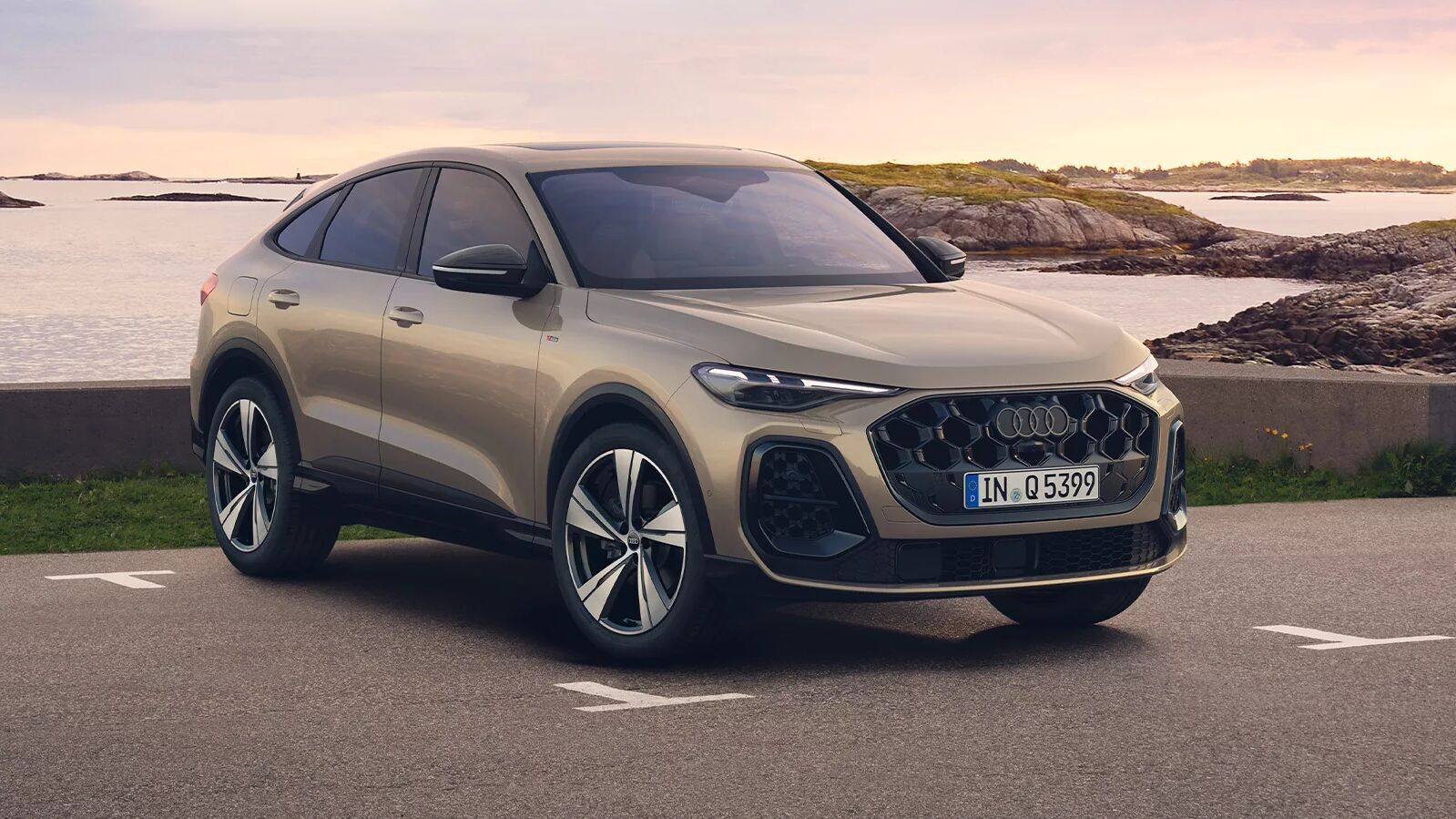 Audi Q5 Sportback Edition One in Sandbeige Metallic mit schwarzen Akzenten steht am Wasser, 21-Zoll-Felgen und LED-Matrix-Scheinwerfer.