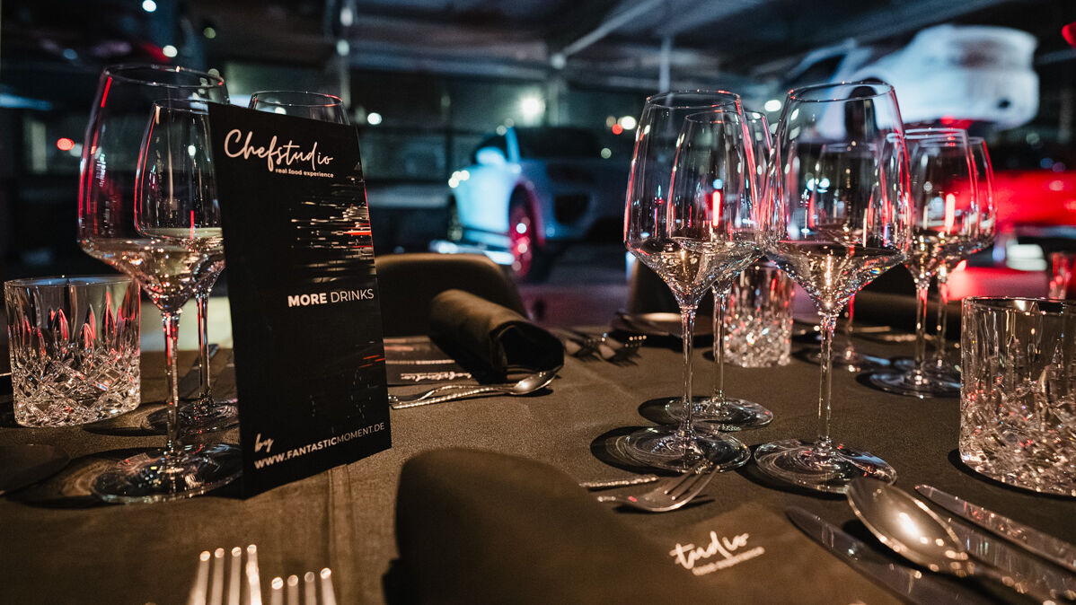 Ein festlich gedeckter Tisch steht zwischen Sportwagen.