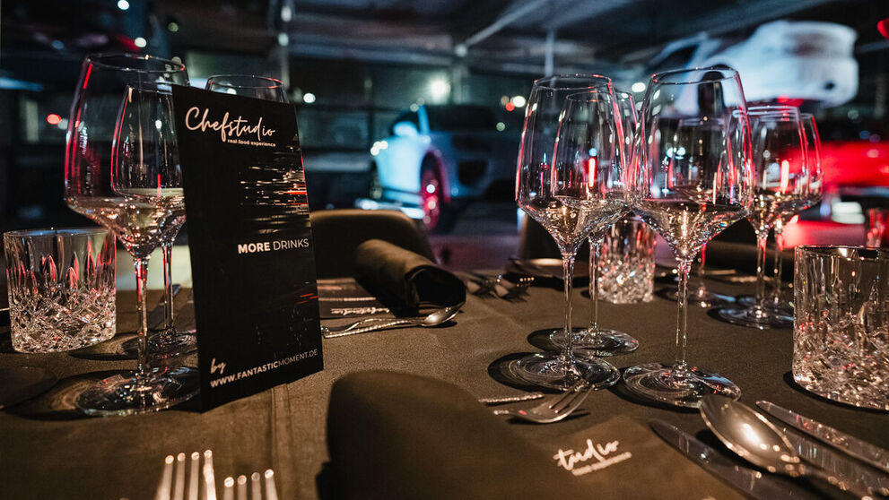 Ein festlich gedeckter Tisch steht zwischen Sportwagen.