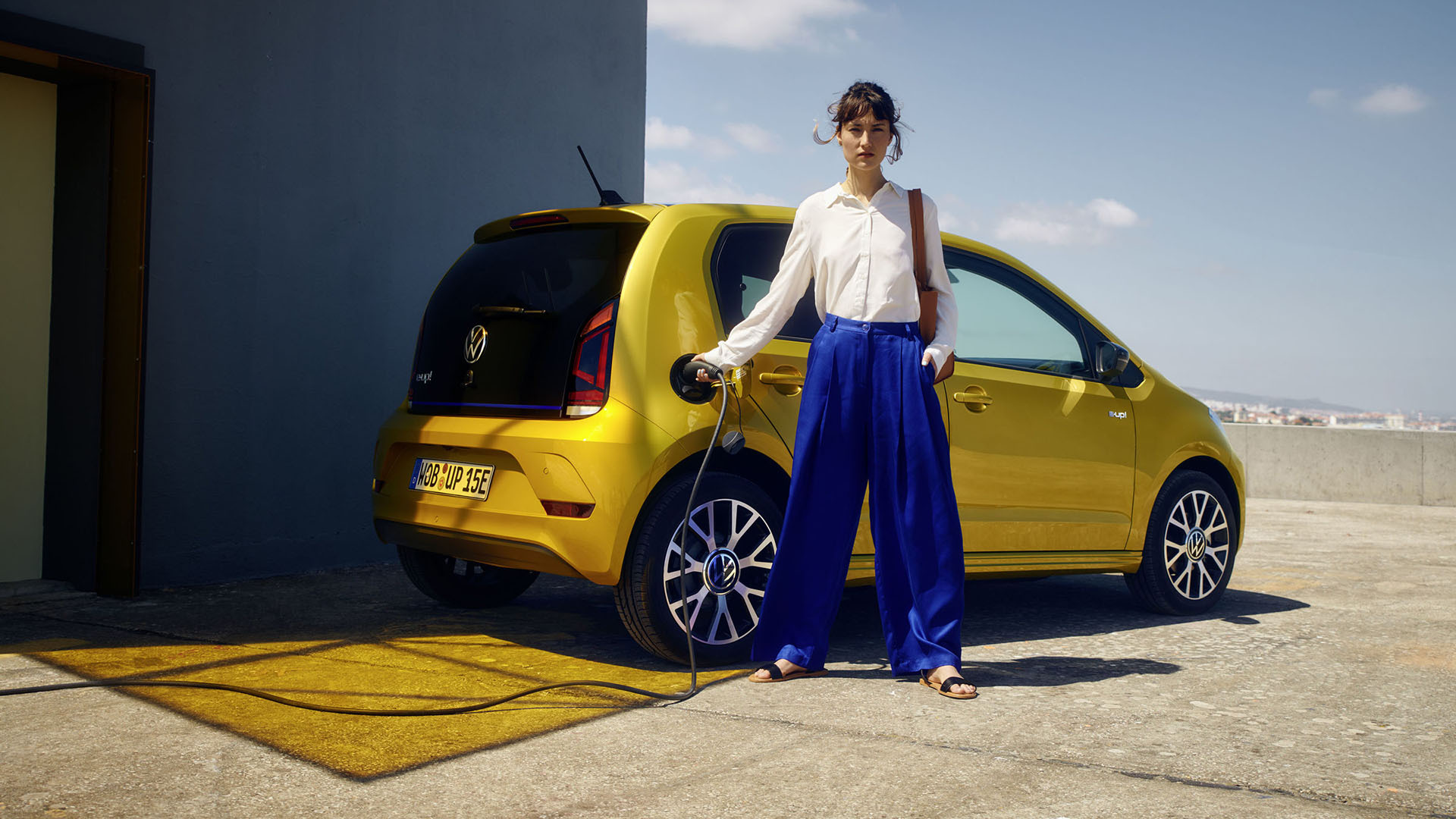 Frau steht neben dem VW e-up! während des Ladevorgangs