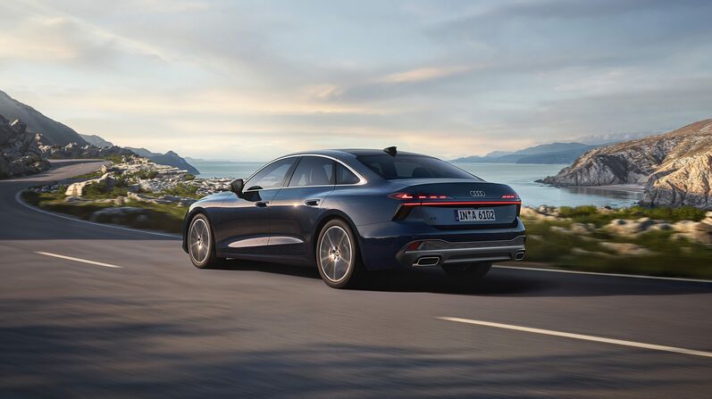 Audi A6 Limousine in Blau Metallic fährt dynamisch die Straße entlang.