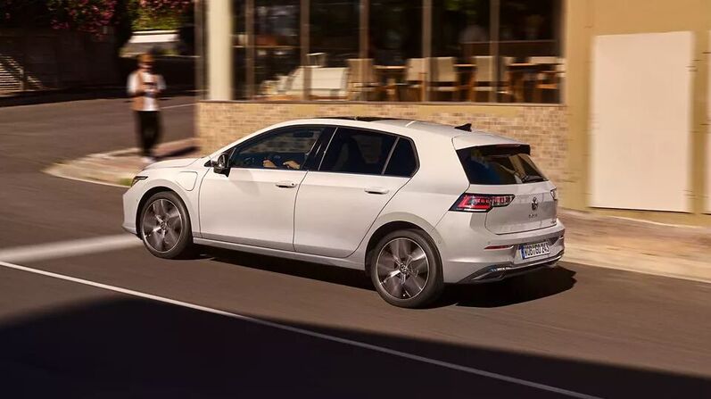 VW Golf in Weiß fährt die Straße entlang.