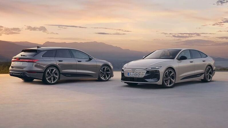 Zwei Audi A6 e-tron Modelle – ein grauer Avant und eine helle Limousine – mit sportlichem Design und großen Felgen vor Bergkulisse im Sonnenuntergang.
