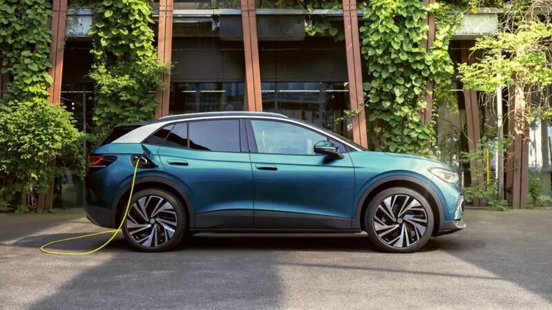 Der VW ID.4 steht seitlich vor moderner, begrünter Architektur und ist sichtbar angeschlossen. Das elektrische SUV verbindet Raumgefühl mit moderner Technik.