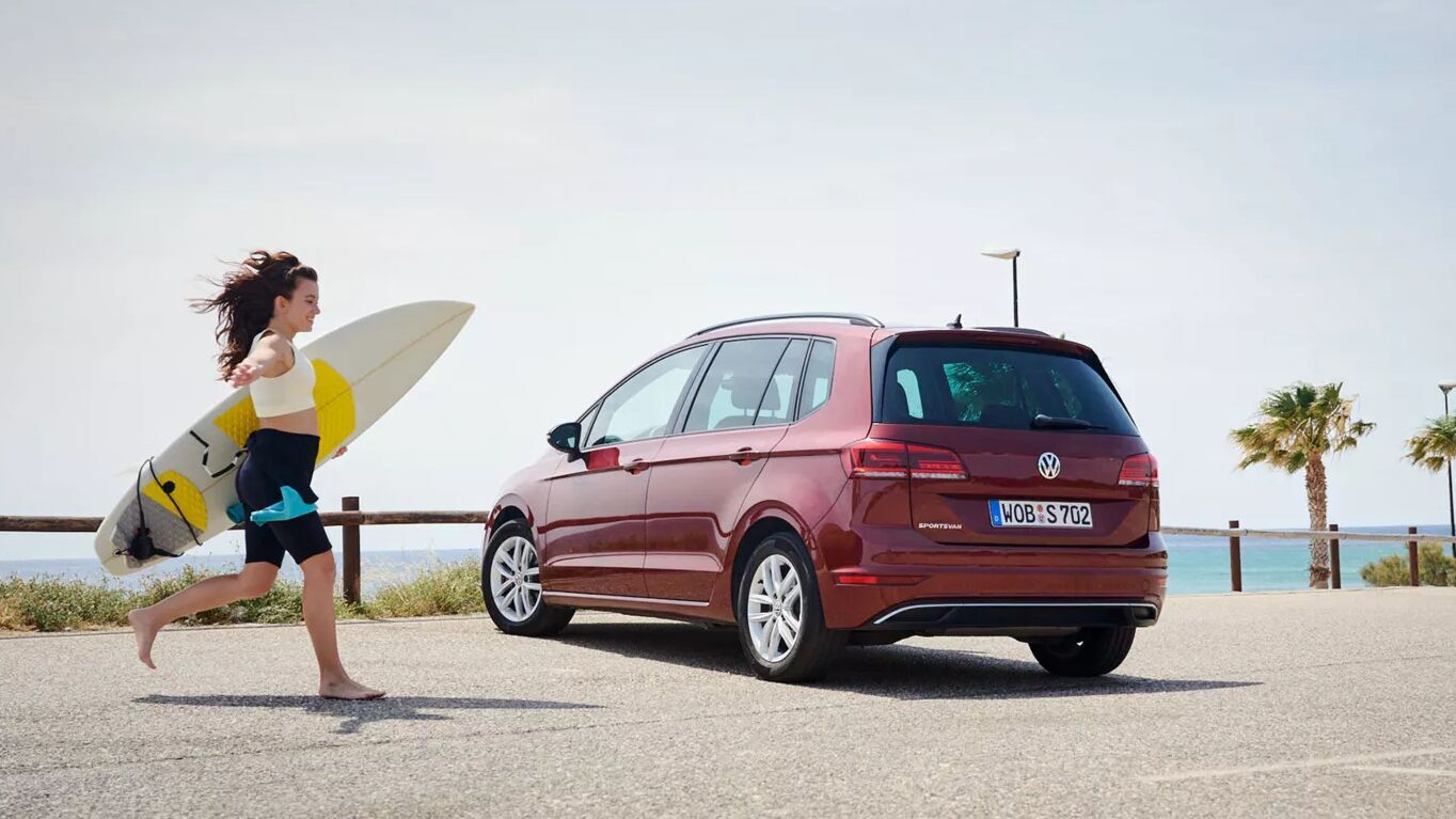 Der rote Golf Sportsvan steht an der Küste. Der erhöhte Innenraum bietet viel Platz und praktische Lösungen für verschiedene Fahrzeugtypen im Alltag.