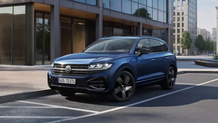 Der blaue VW Touareg präsentiert sich souverän vor moderner Glasfassade. Hochwertige Details und starke Präsenz machen ihn zum Spitzenmodell im Portfolio.