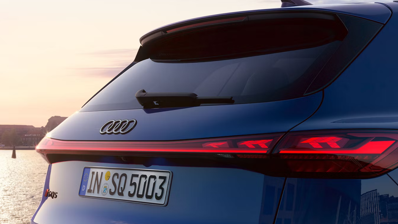 Audi SQ5 in Utranablau Metallic, zeigt das Heck mit durchgehendem LED-Lichtband, Oled Heckleuchten Q5-Logo und sportlichem Dachspoiler.