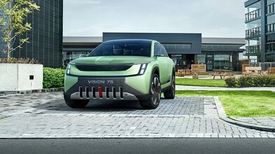 Der Vision 7S steht vor moderner Architektur und zeigt seine klare Designsprache mit markanter Front. Das Fahrzeug wirkt modern solide.
