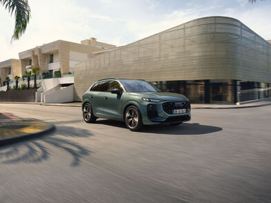 Der neue Audi Q3 in grün in dynamischer Fahrt in einer modernen Stadt