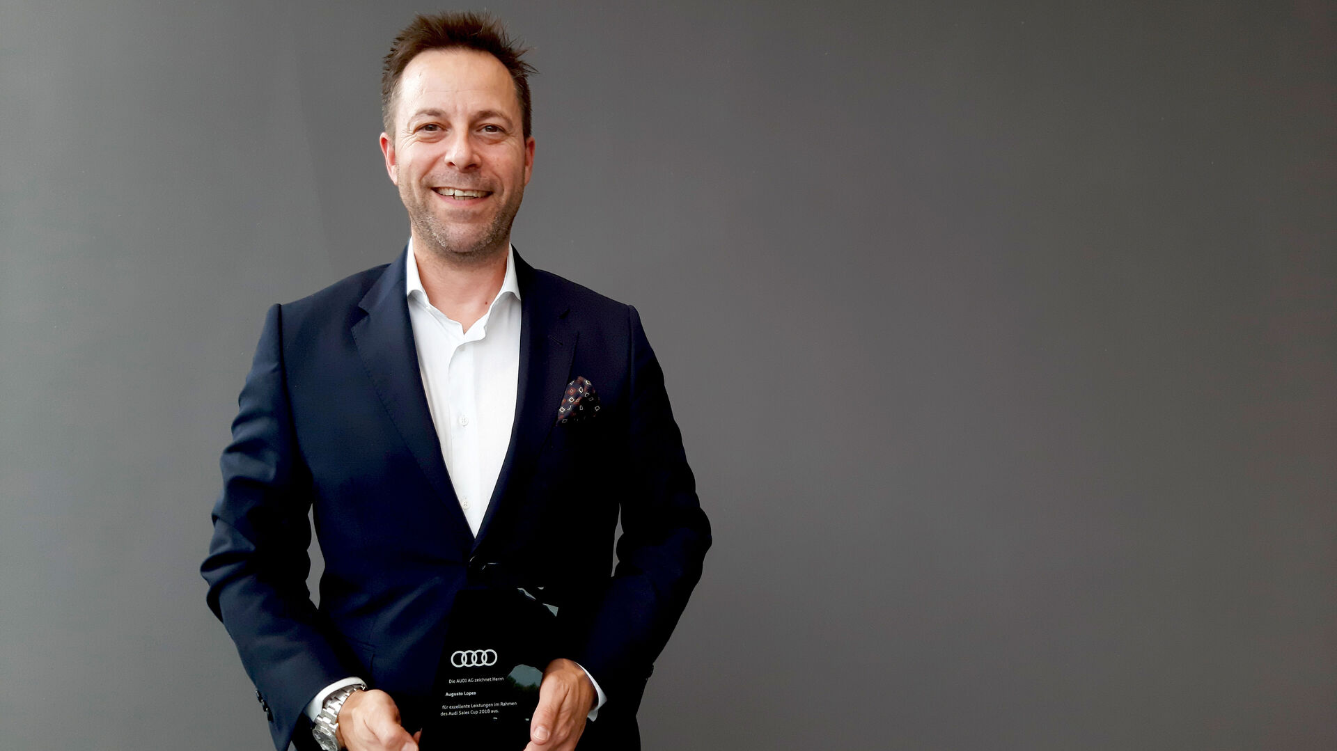 Audi Neuwagen Verkaufsberater Augusto Lopes präsentiert seine Auszeichnung der Audi AG