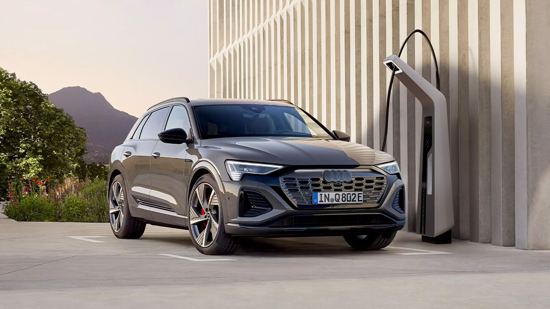 Der Audi Q8 e-tron in grauer Lackierung kombiniert markanten Singleframe-Grill, aerodynamische Linienführung, schmale LED-Scheinwerfer und große, präzise gefertigte Leichtmetallfelgen.