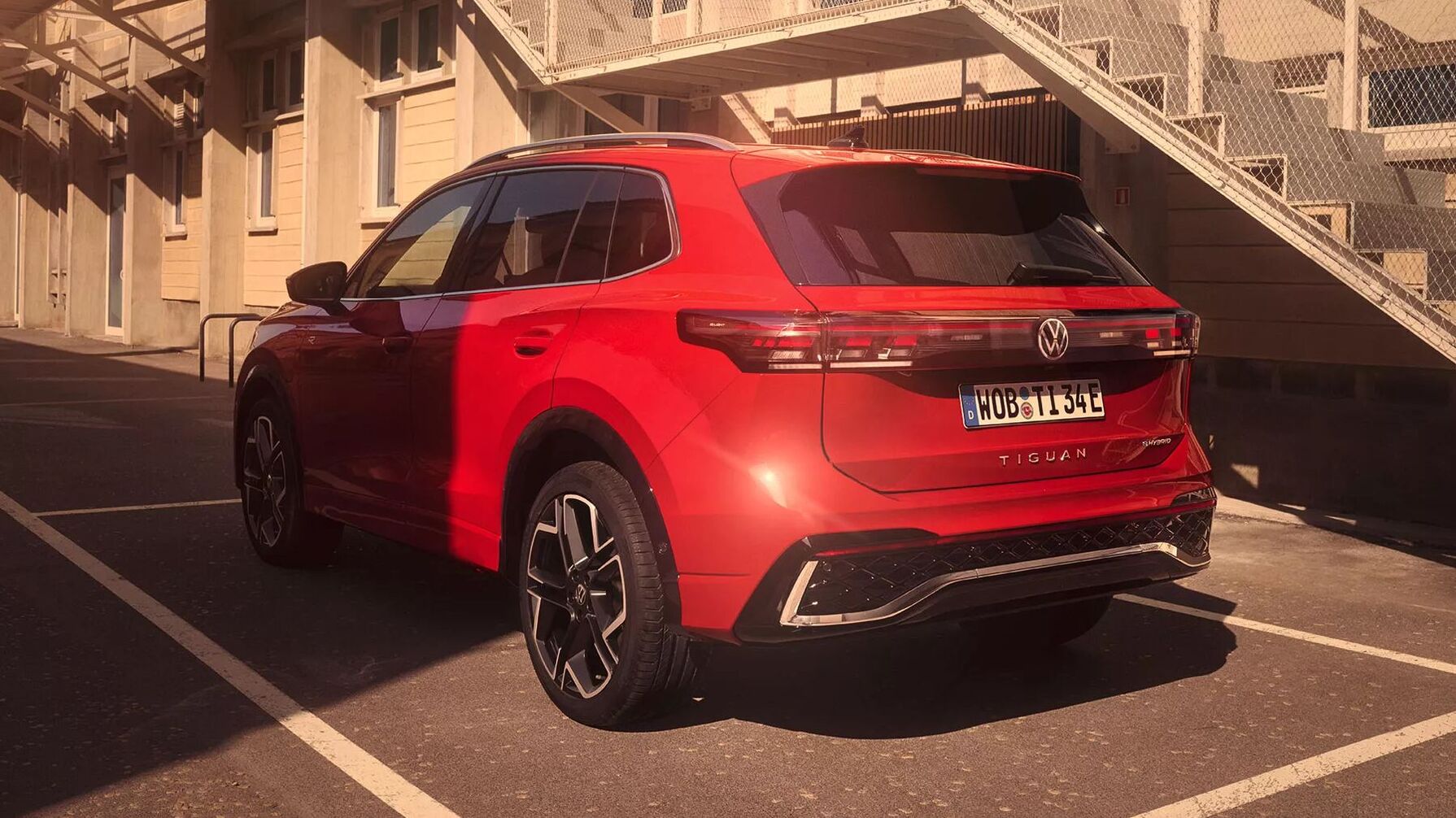 Der rote VW Tiguan steht im Licht moderner Architektur. Das SUV verbindet klare Linien mit vielseitiger Einsetzbarkeit und gehört zu den beliebtesten Fahrzeugtypen im Segment.