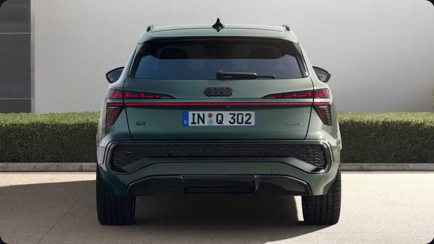Der Audi Q3 in grüner Lackierung zeigt sich mit markanter Heckansicht, durchgehender LED-Lichtleiste, klar strukturiertem Stoßfänger und kraftvoller SUV-Optik.